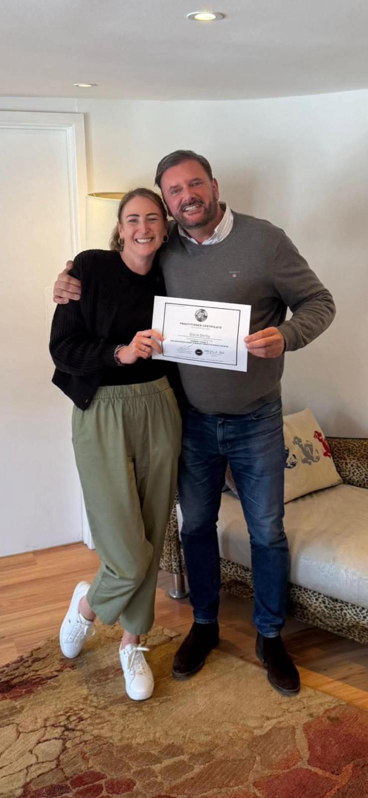 Stacie holding her Unconscious Mind Therapy practitioner certificate