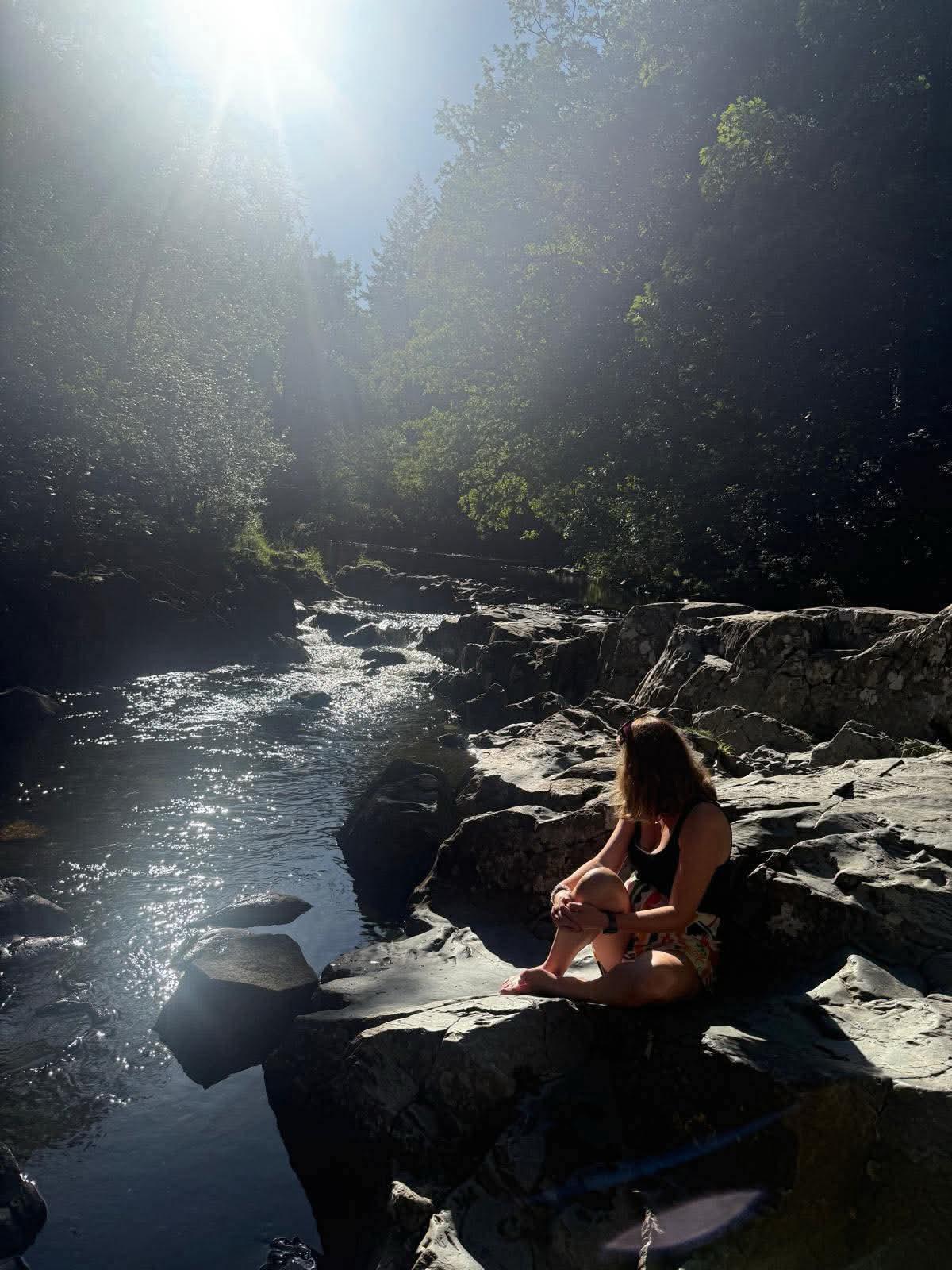 Stacie sitting beside a sunlit river